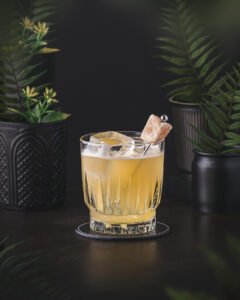 Penicillin Cocktail - Yellow whisky drink served in a atumbler on ice. Garnished with ginger.