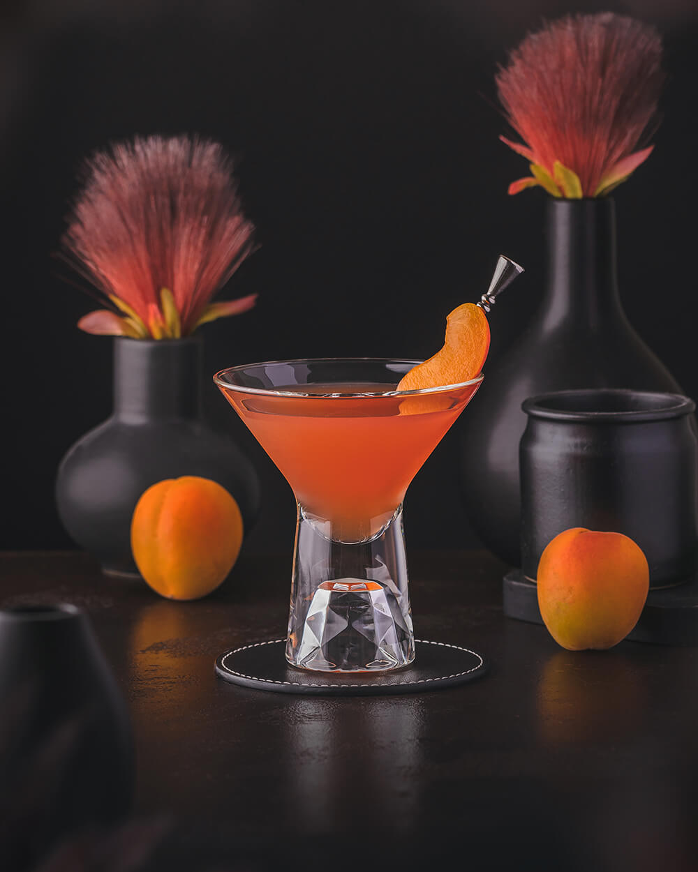 Charlie Chaplin Cocktail - Orange red classic cocktail made with sloe gin, apricot liqueur and lime juice. Garnished with an apricot wedge.